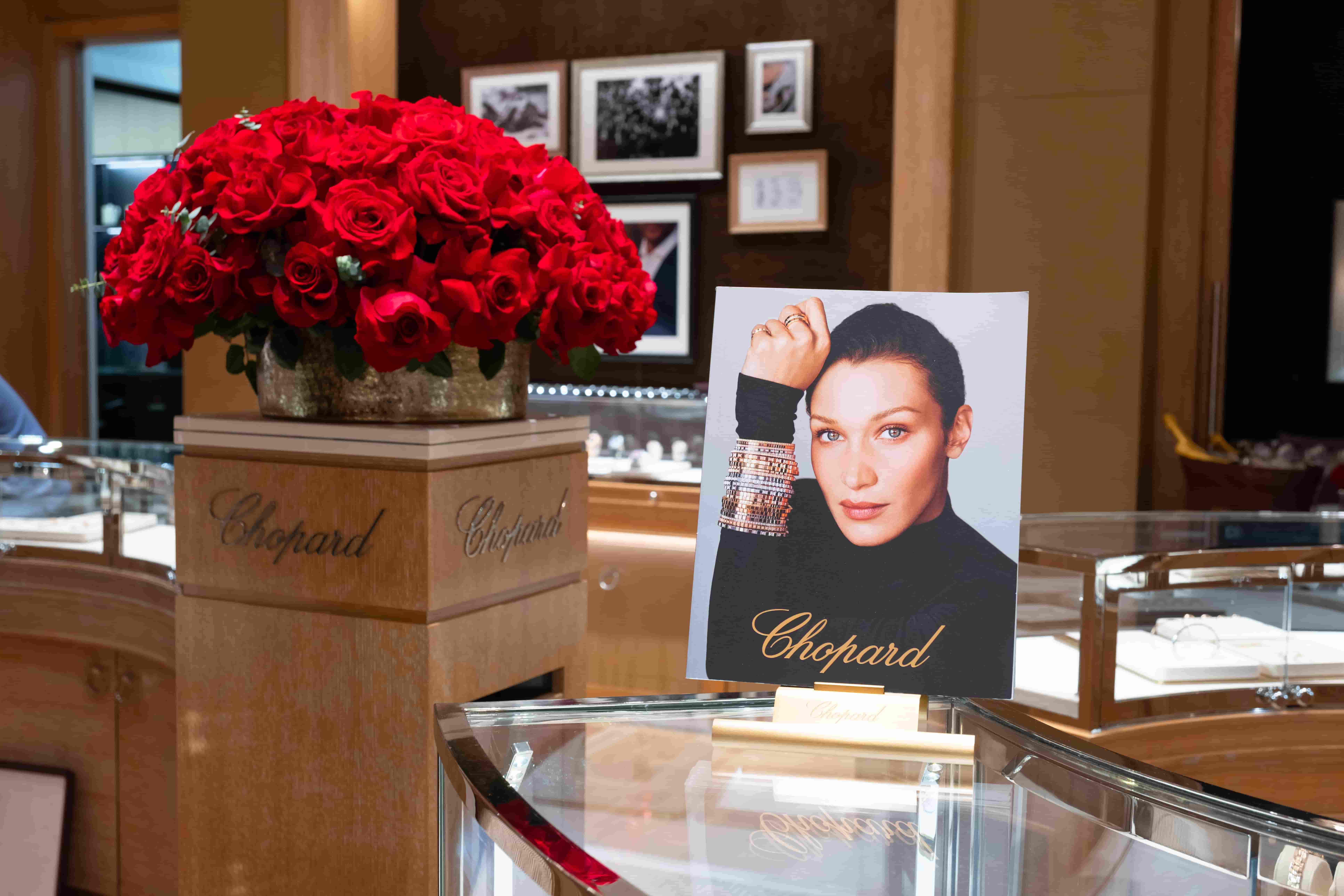 Chopard boutique interior featuring a large bouquet of red roses and a promotional display with a model wearing luxury jewelry.
