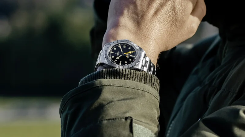 A man wearing a tudor watch with a black dial.