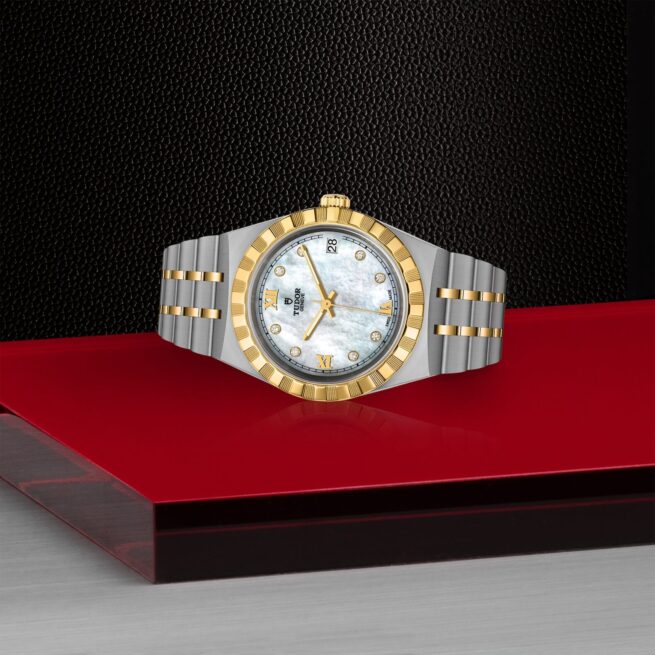 A gold and silver M28403-0007 watch on a red table.