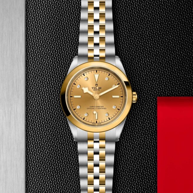 A gold and silver M79683-0008 watch on a black background.