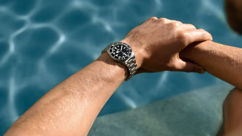 A man wearing a watch next to a swimming pool.