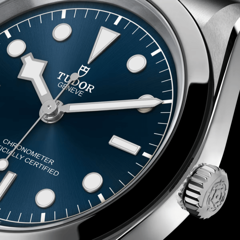 Close-up of a Tudor M79600-0002 wristwatch with a blue dial, showing silver hour markers, hands, and a crown with the Tudor logo. The watch face reads "Chronometer Officially Certified".