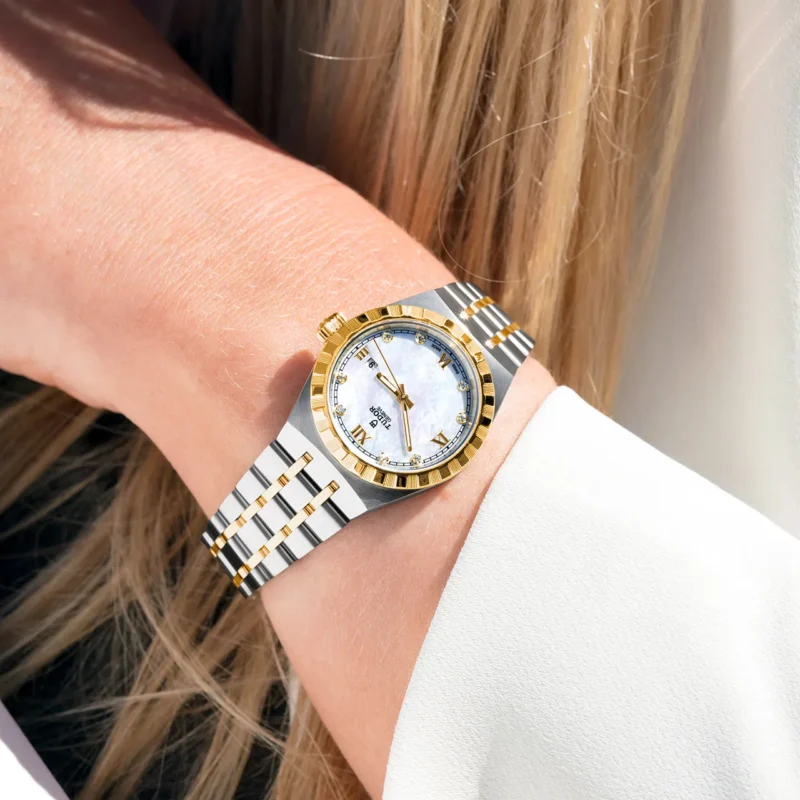 A woman's wrist with a M28403-0007 gold and white watch.