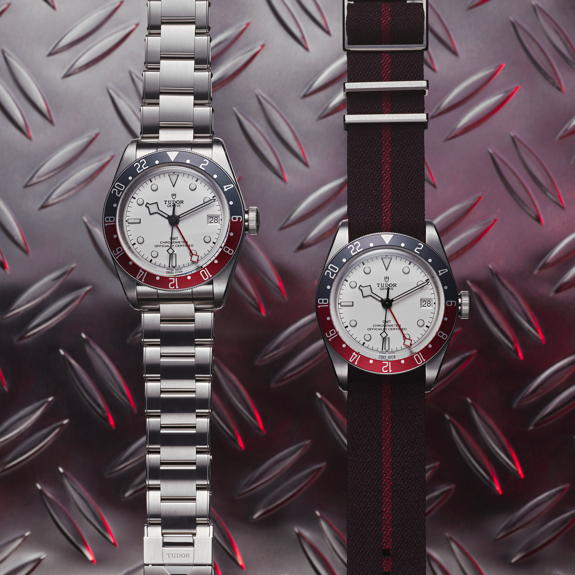 Three M79833MN-0004 watches on a metal surface with red, white and blue dials.