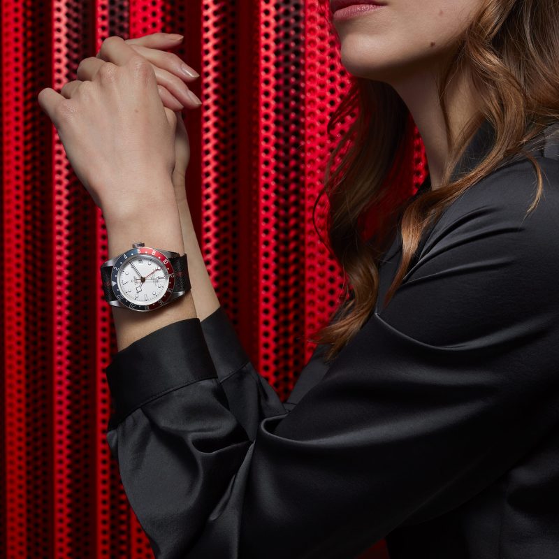 A woman wearing a black shirt and a red M79833MN-0004 watch.