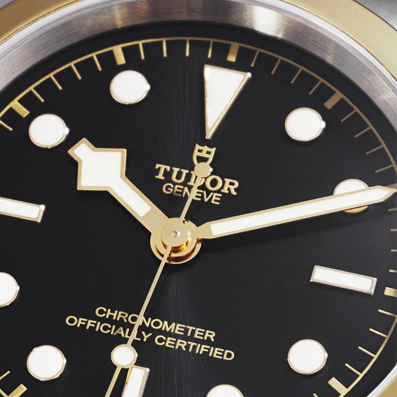 Close-up of a Tudor watch face, showing the hour, minute, and second hands, along with circular and rectangular markers. The text "Tudor Geneva" and "Chronometer Officially Certified" is visible. The product name is M79643-0001.