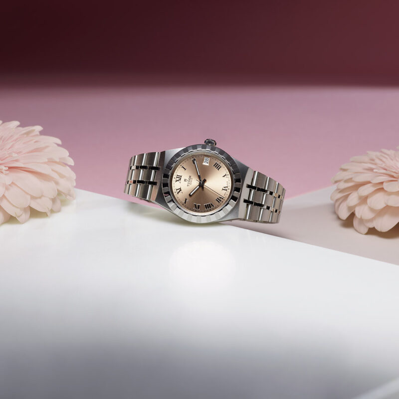 A M28600-0009 watch sitting on a table next to flowers.