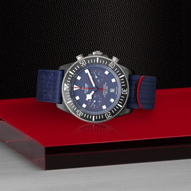 A M25807KN-0001 with a blue strap sitting on a red surface.