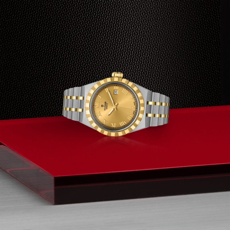 A yellow and gold M28303-0004 watch on a red table.