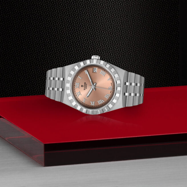 A M28400-0009 watch with a rose gold dial sitting on a red table.