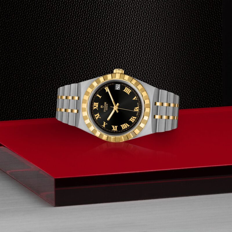 A gold and silver M28403-0003 watch on a red table.