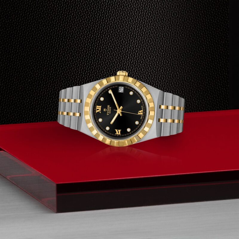 A gold and silver M28403-0005 watch on a red table.