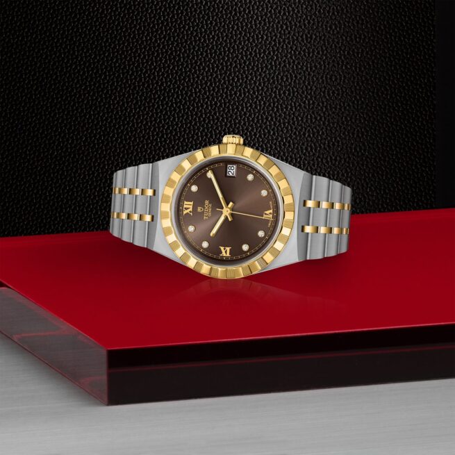 A gold and silver M28403-0009 watch on a red table.