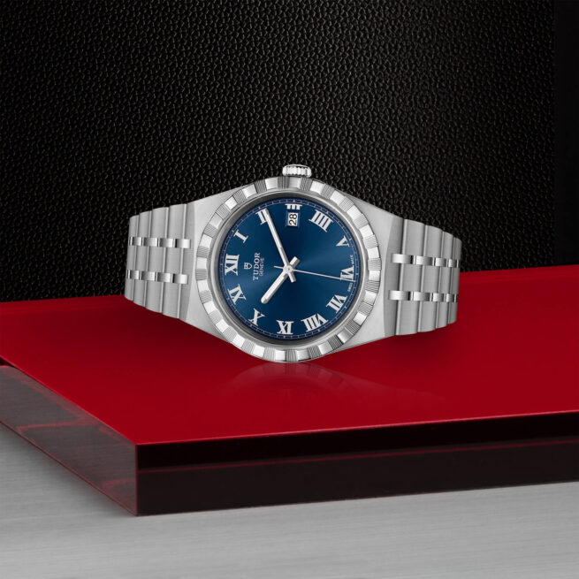 A M28500-0005 oyster blue dial watch on a red table.