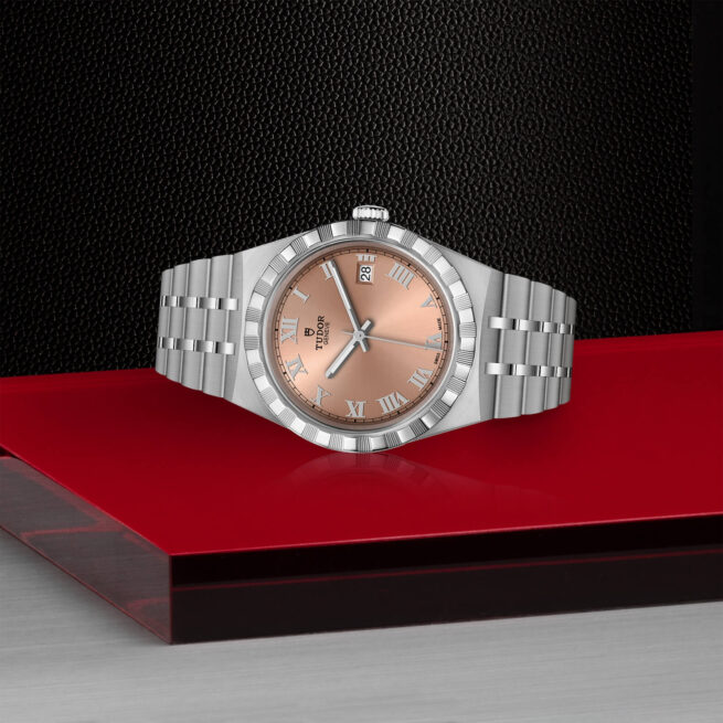 A M28500-0007 watch with a rose gold dial on a red background.