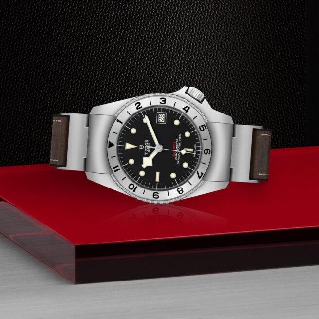 The M70150-0001 watch is sitting on a red table.