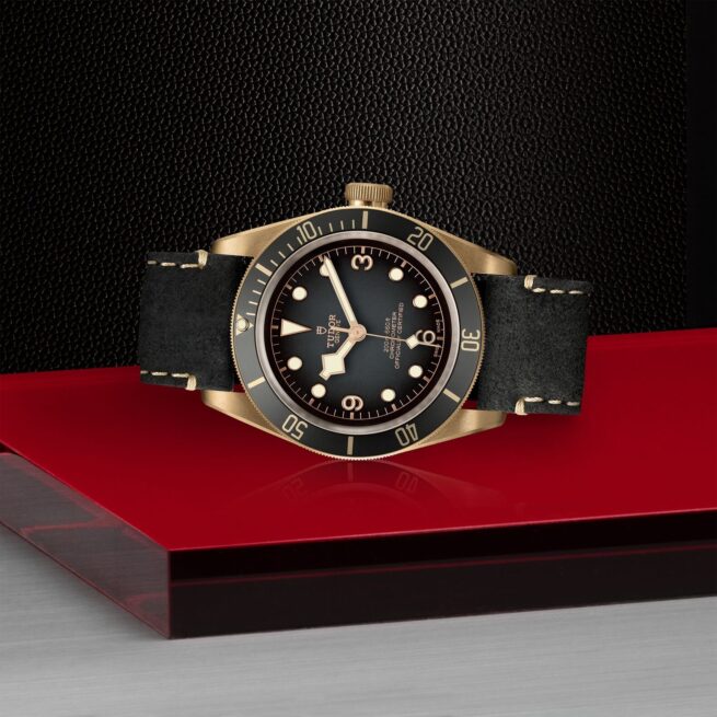 The M79250BA-0001 watch on a red table.