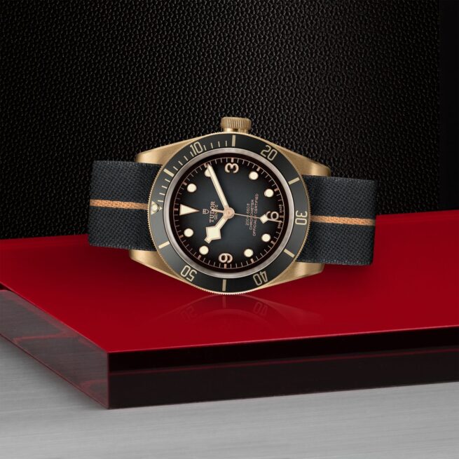 The M79250BA-0002 watch is sitting on a red table.