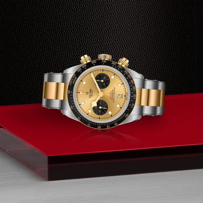 A yellow and gold M79363N-0007 watch on a red table.