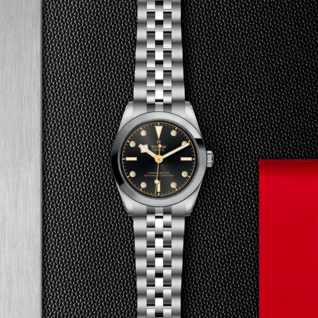 A M79600-0004 watch with a black dial on a red background.