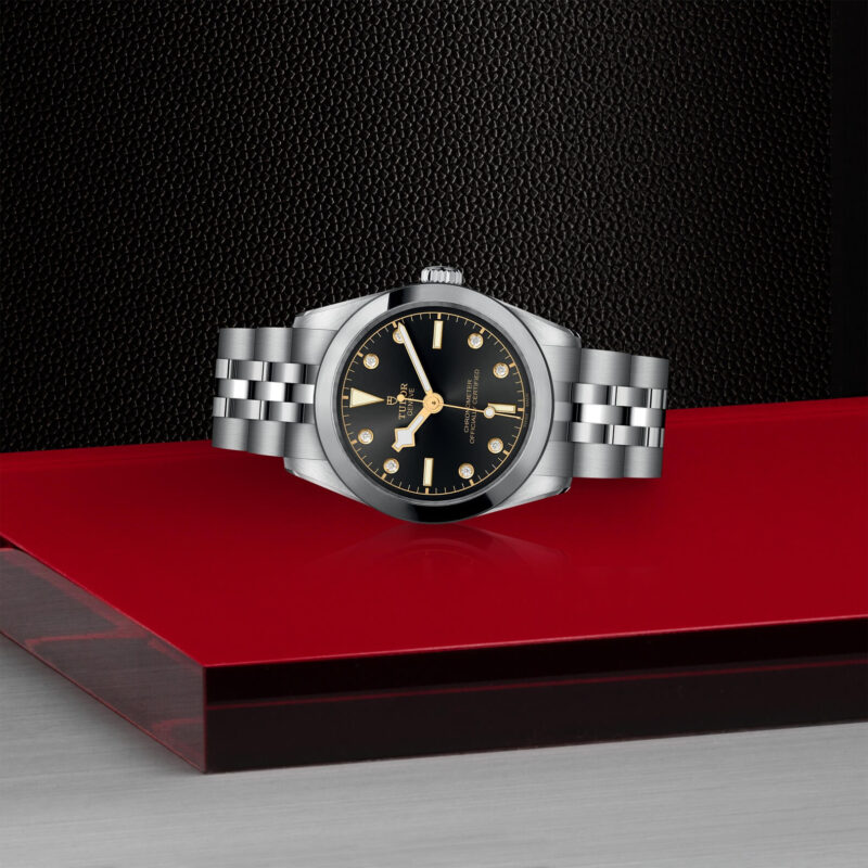 A M79600-0004 watch with a black dial on a red table.