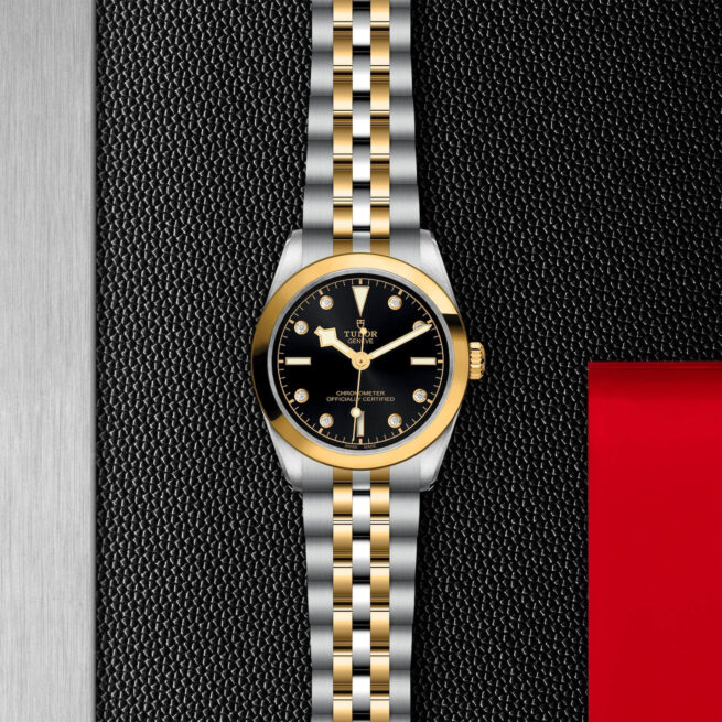 A M79603-0006 watch with a black dial on a red background.