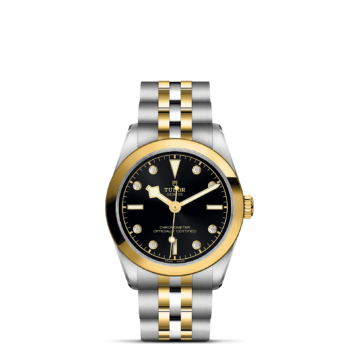 A M79603-0006 watch with a black dial and yellow gold bezel.