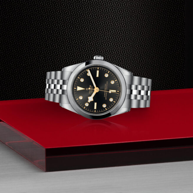 A M79640-0004 watch with a black dial on a red background.