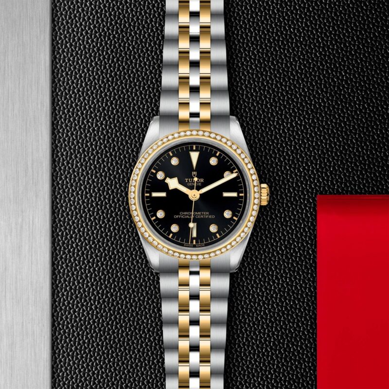 A black and gold M79653-0005 watch on a red background.