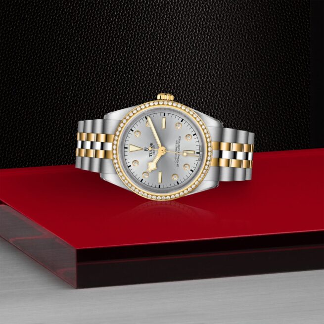 A M79653-0006 watch with diamonds on a red background.