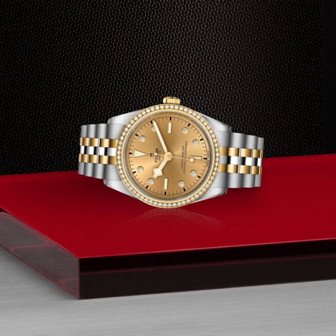 A M79653-0007 watch with diamonds on a red table.