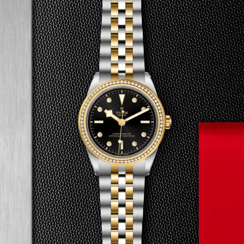 A black and gold M79673-0006 watch on a red background.