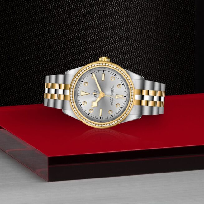A M79673-0005 watch with diamonds on a red table.
