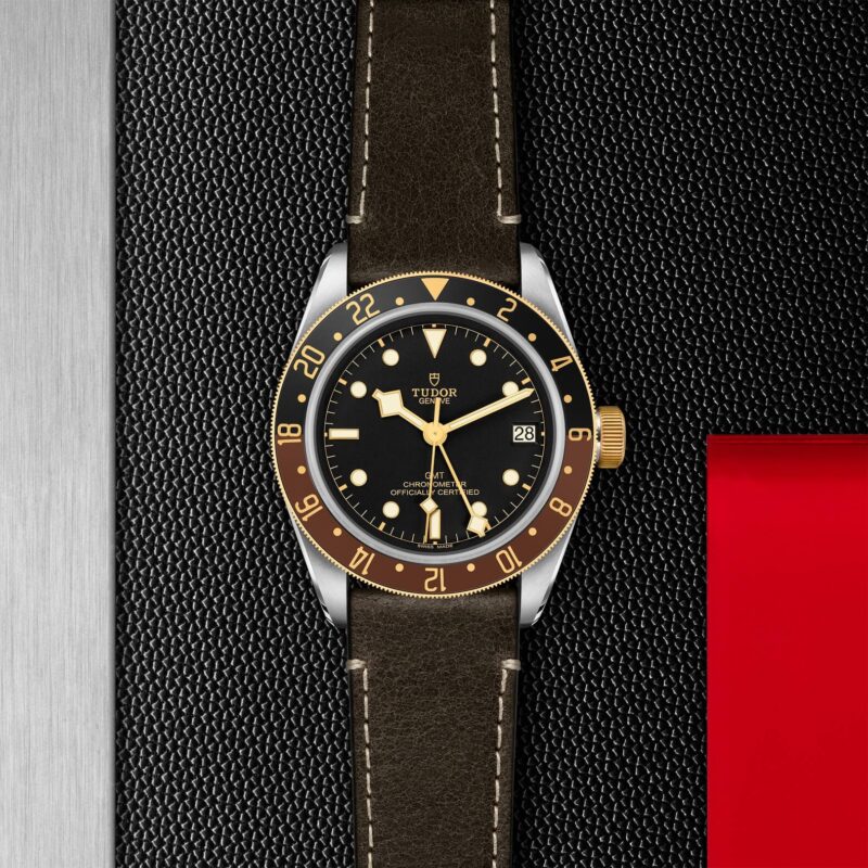 The M79833MN-0003 watch is sitting on a red leather strap.