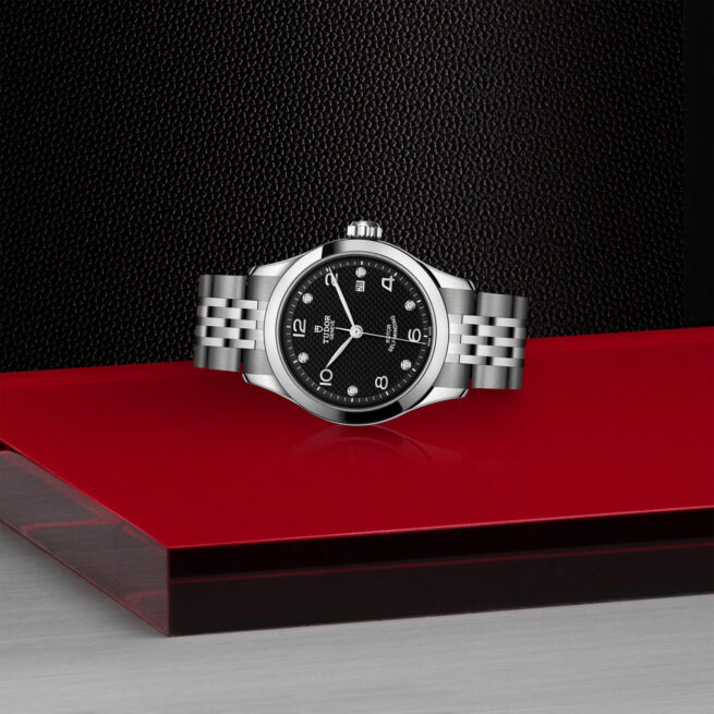 A M91350-0004 watch sitting on a red table.