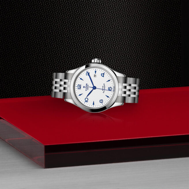 A M91350-0005 with a blue dial sitting on a red table.