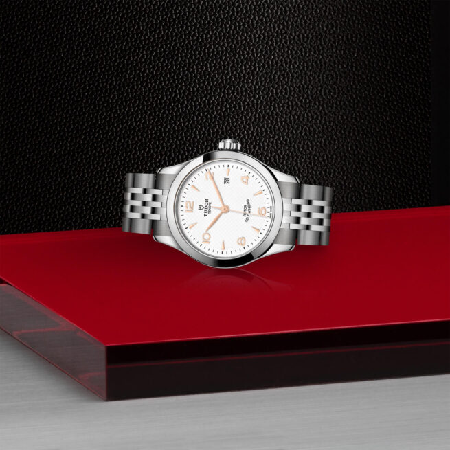 A M91350-0011 watch sitting on a red surface.