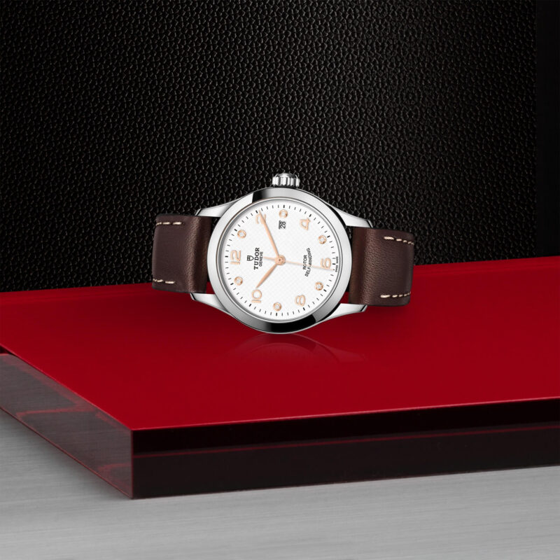 A M91350-0014 with a brown leather strap sitting on a red surface.