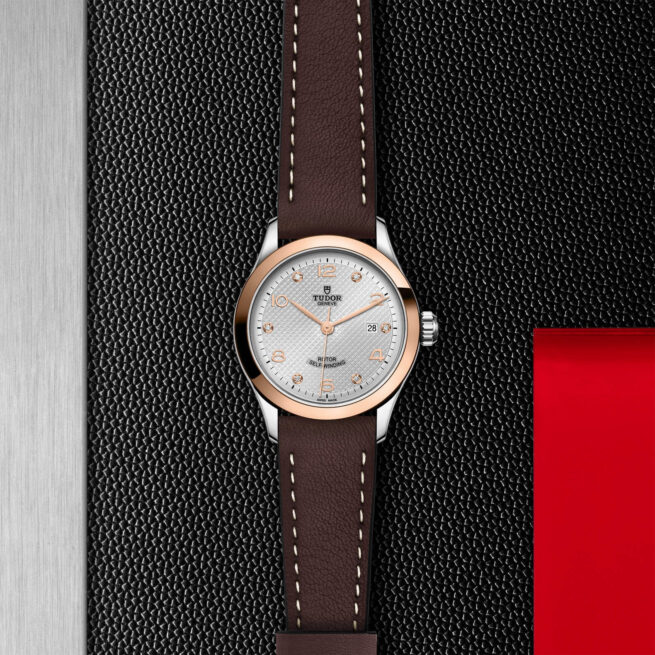 A watch with a brown leather strap (M91351-0006) on a red background.