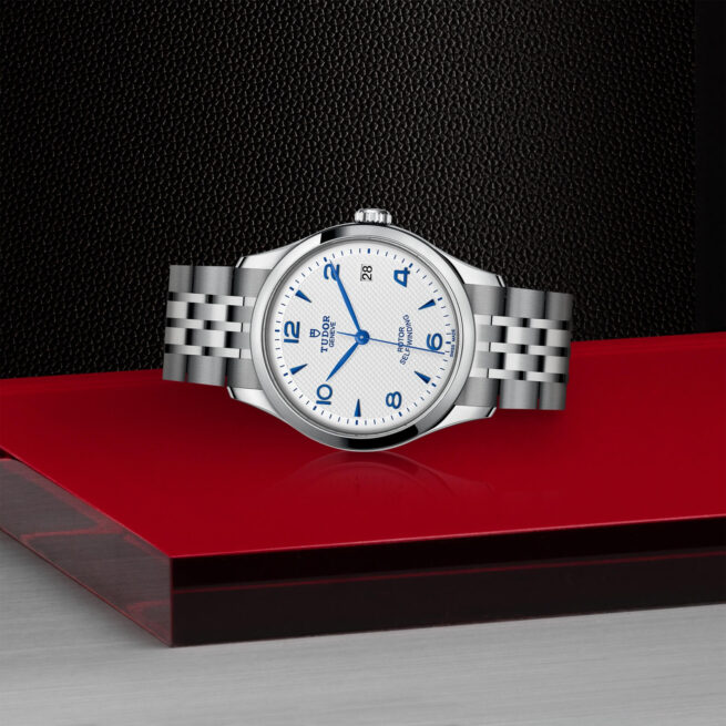 A M91450-0005 watch with blue dial sitting on a red table.