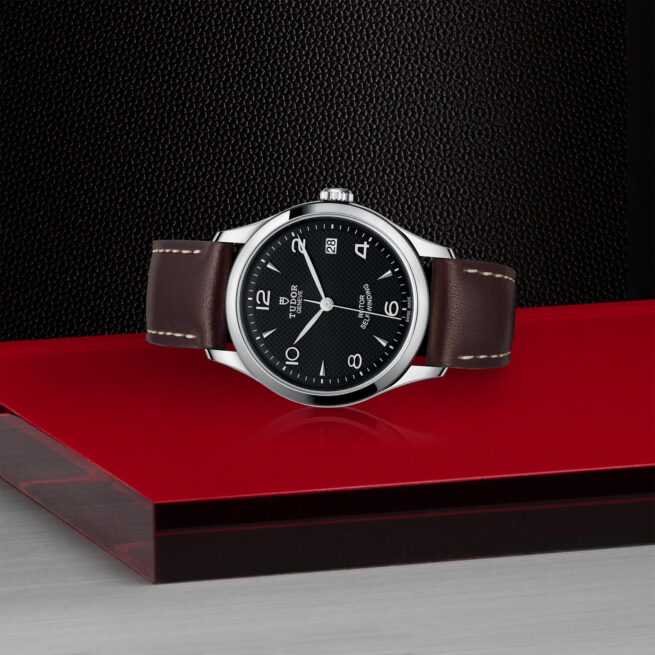 A M91450-0008 watch sitting on a red surface.