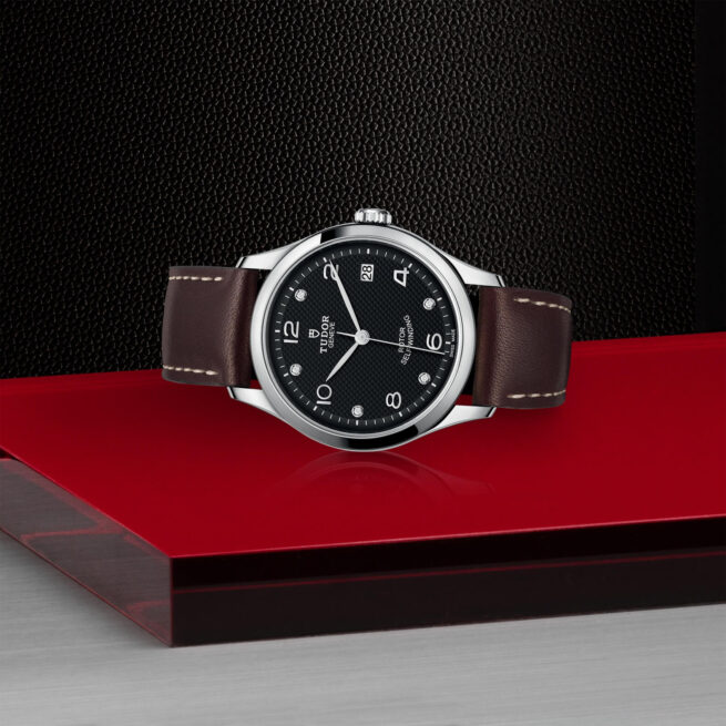 A M91450-0009 watch sitting on a red surface.