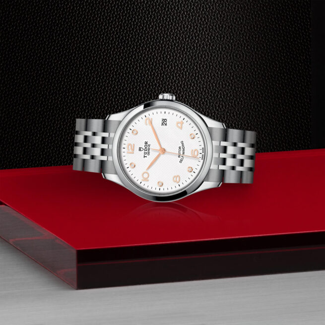 A M91450-0013 watch sitting on a red table.