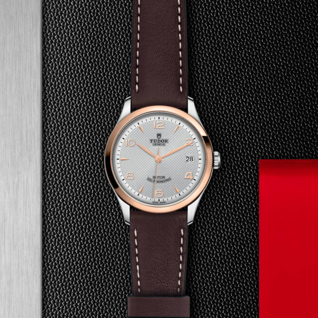 A M91451-0005 with a brown leather strap on a red background.