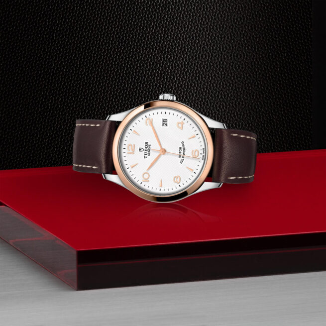 A M91451-0010 with a brown leather strap sitting on a red surface.