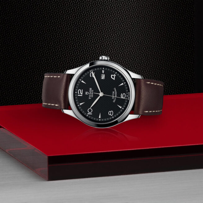 A M91550-0008 watch sitting on a red table.