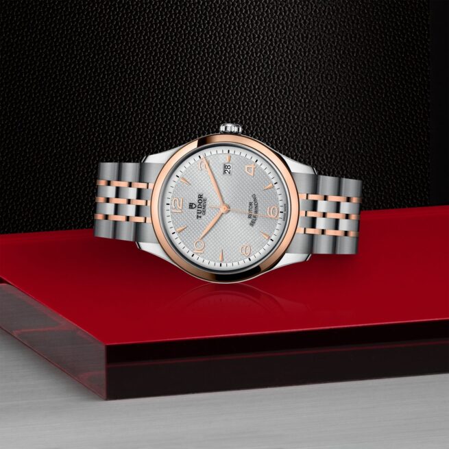 A white and silver M91551-0001 watch on a red surface.