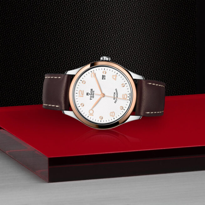 A M91551-0012 with a brown leather strap sitting on a red surface.