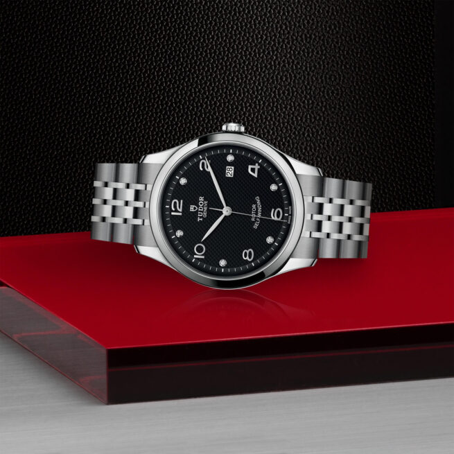 A M91650-0004 watch sitting on a red surface.