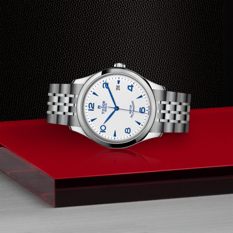 A M91650-0005 watch with a blue dial sitting on a red surface.